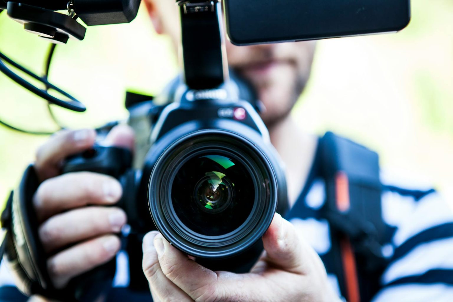 Campagnes de Désinformation dans la Fintech : Le Cas Zaki Farooq A close-up shot of a cameraman filming, focusing on the camera lens and equipment.