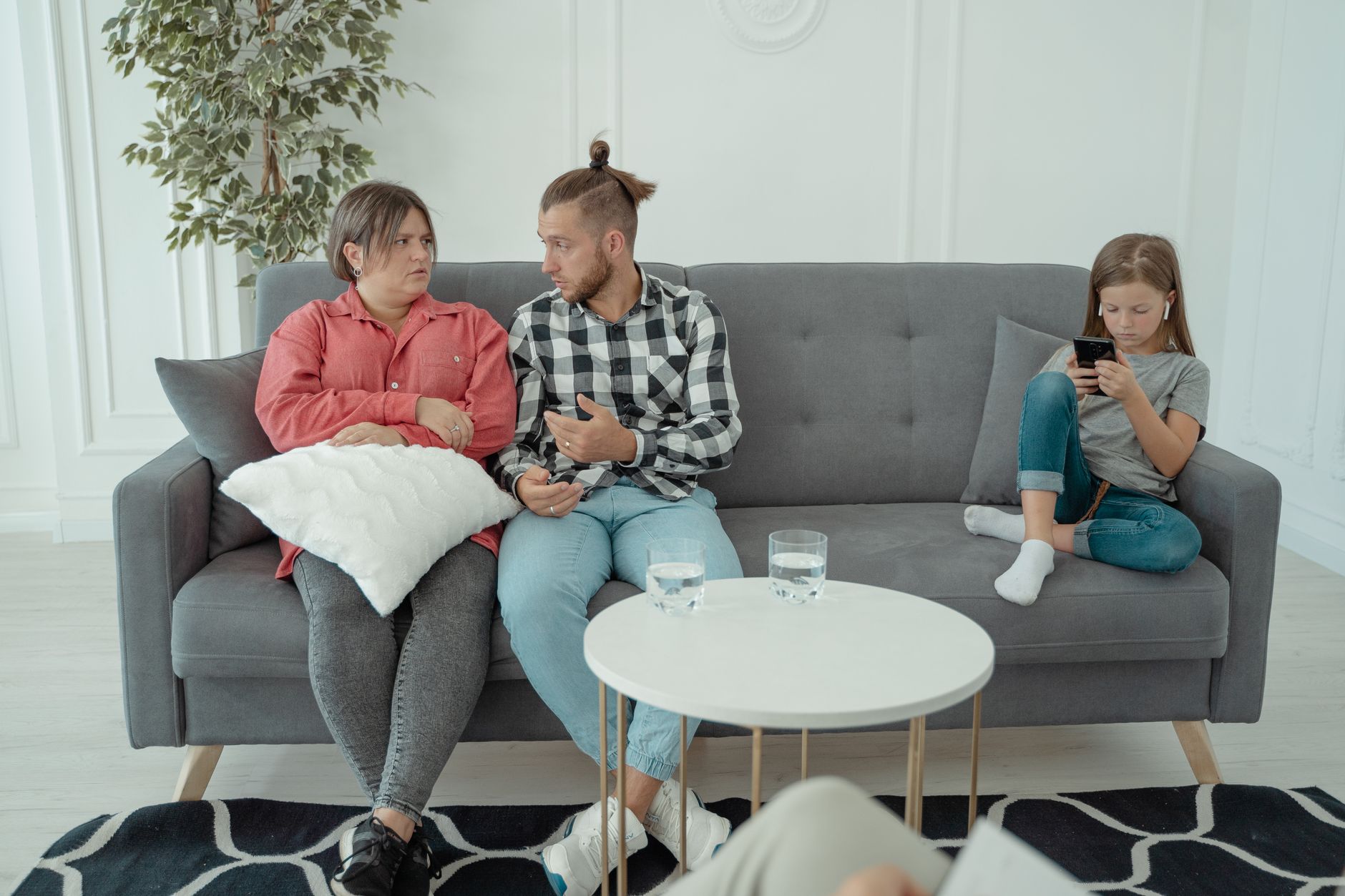 Une séance de thérapie familiale avec des parents qui discutent pendant qu'un enfant est absorbé par son smartphone.