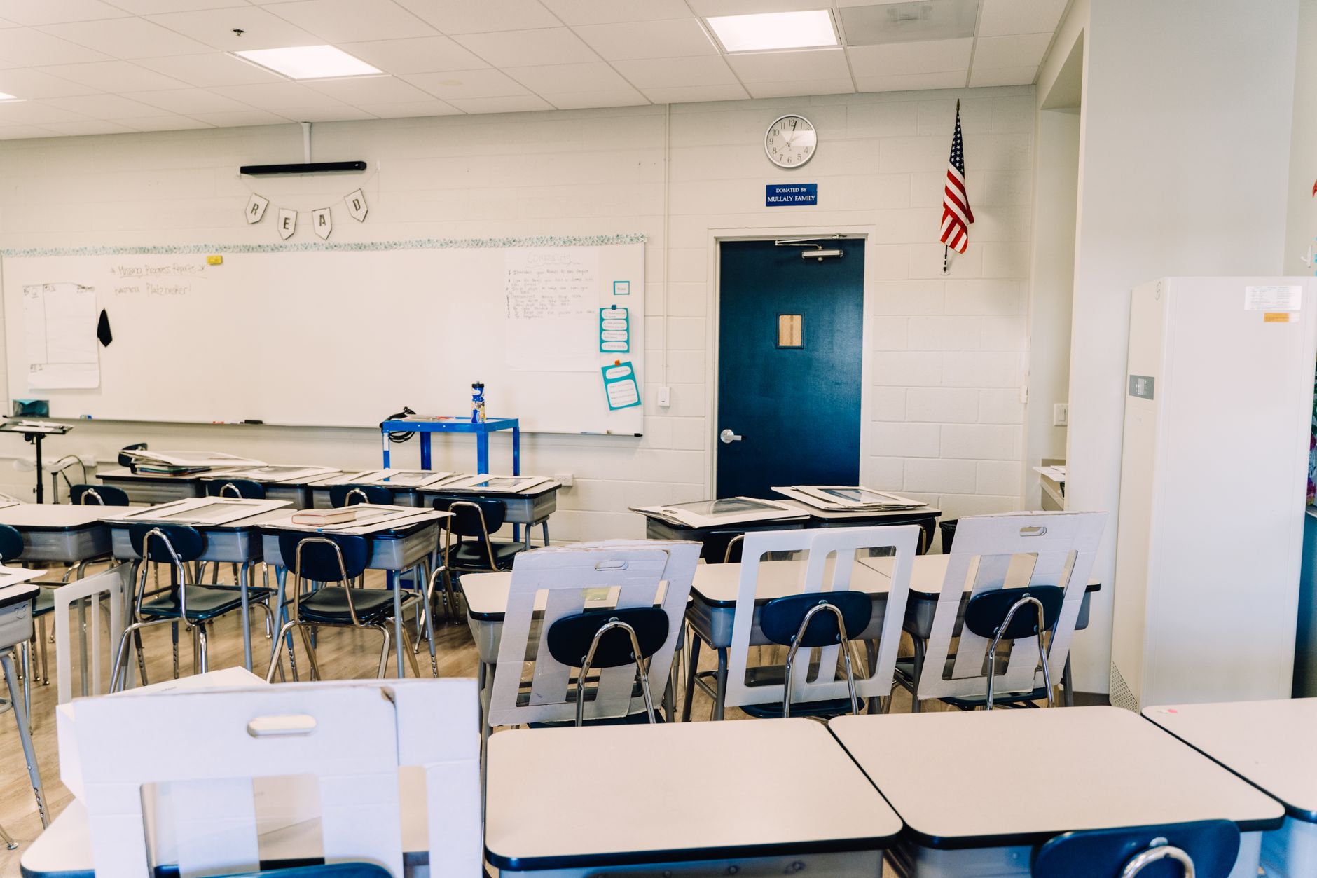 Classe lumineuse et vide comprenant des bureaux, un tableau blanc et un drapeau américain. Environnement d'apprentissage idéal.